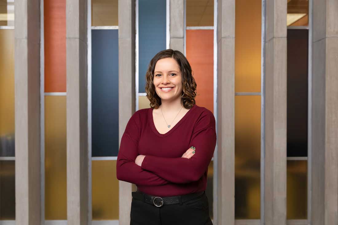 Mackenzie is posed in front of a colored glass wall