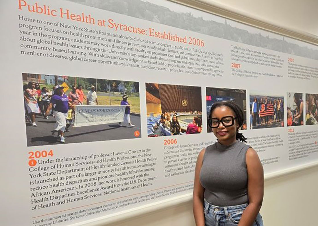 Miriam standing in front of public health mural