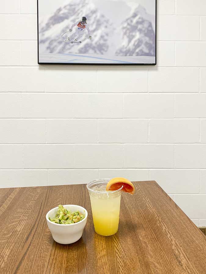A bowl of guacamole and a glass of orange juice on a table