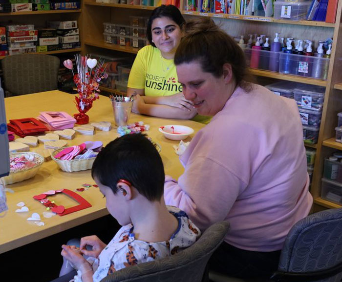 students doing valentines craft with younger male child