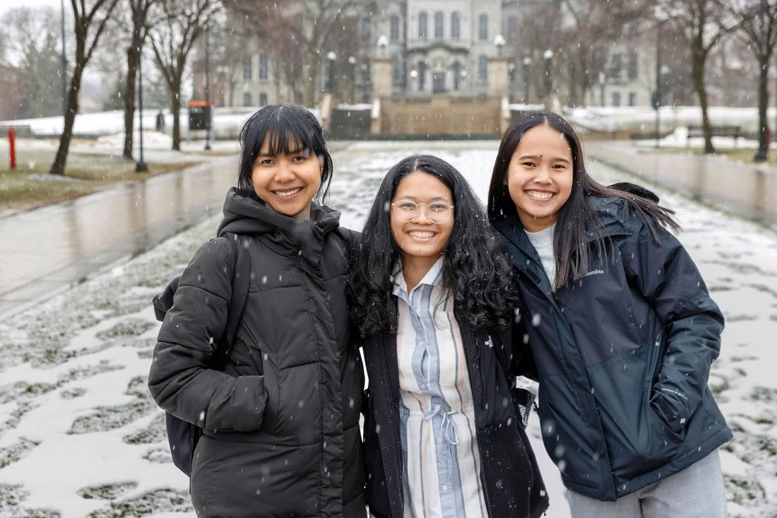 Three students pose together on snowy campus