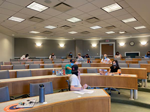 Students are sitting apart from each other with masks in a large classroom