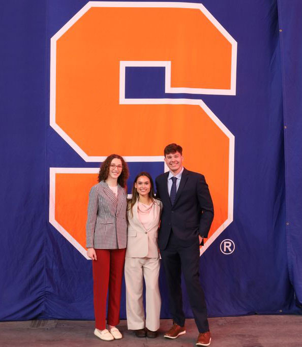 co chairs of charity committee standing together in front of big orange S, Syracuse University logo