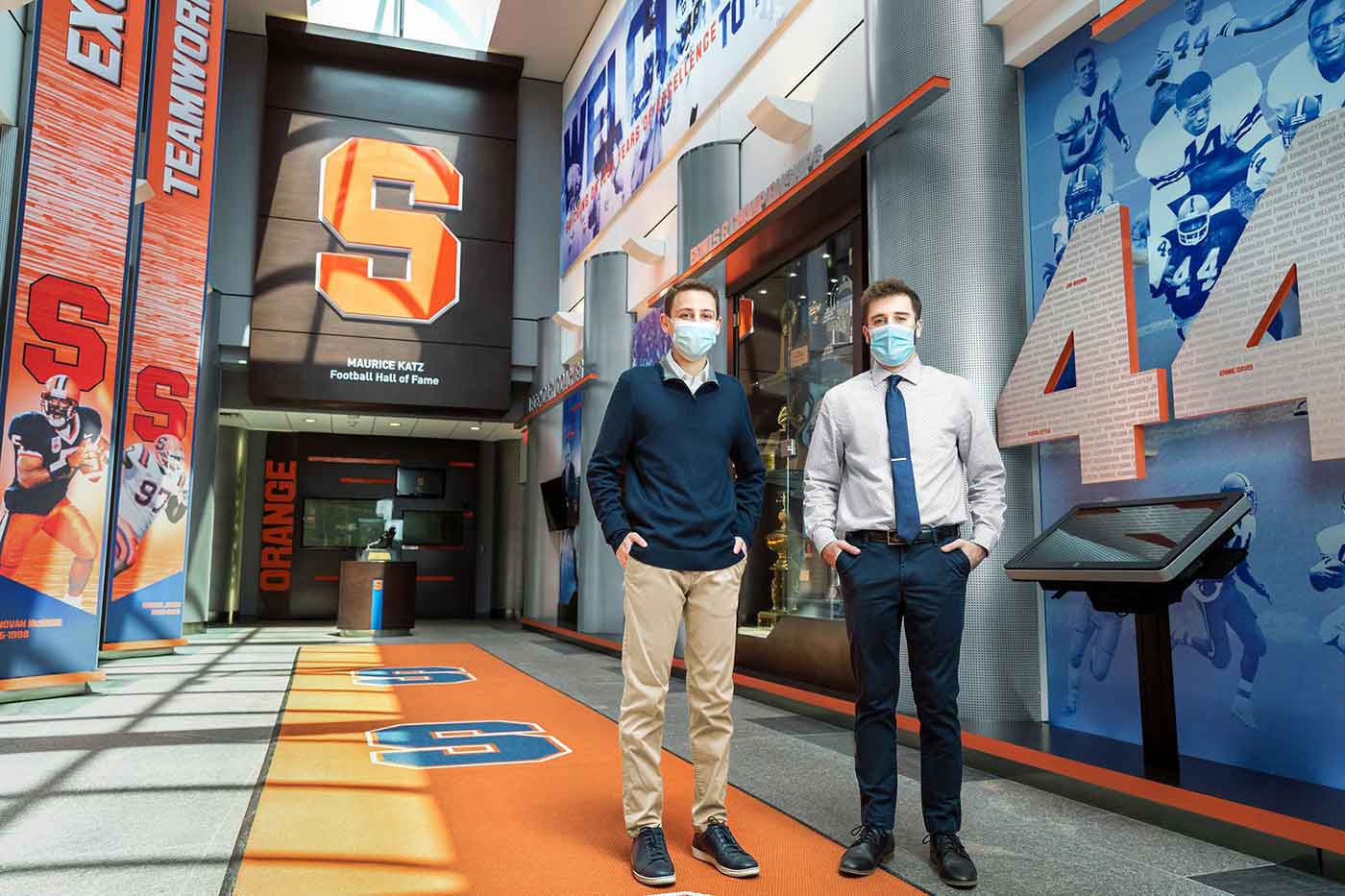 Two students stand in a sport arena lobby