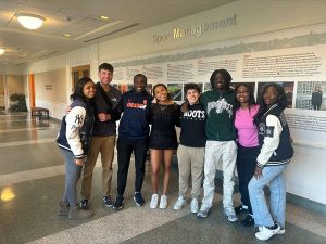 Eight members of the Sport Professioanls of Color Club standing together in the hallway of Sports Management