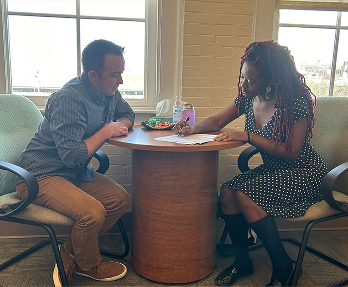Young man and young woman sitting across from each other reviewing a document on the table